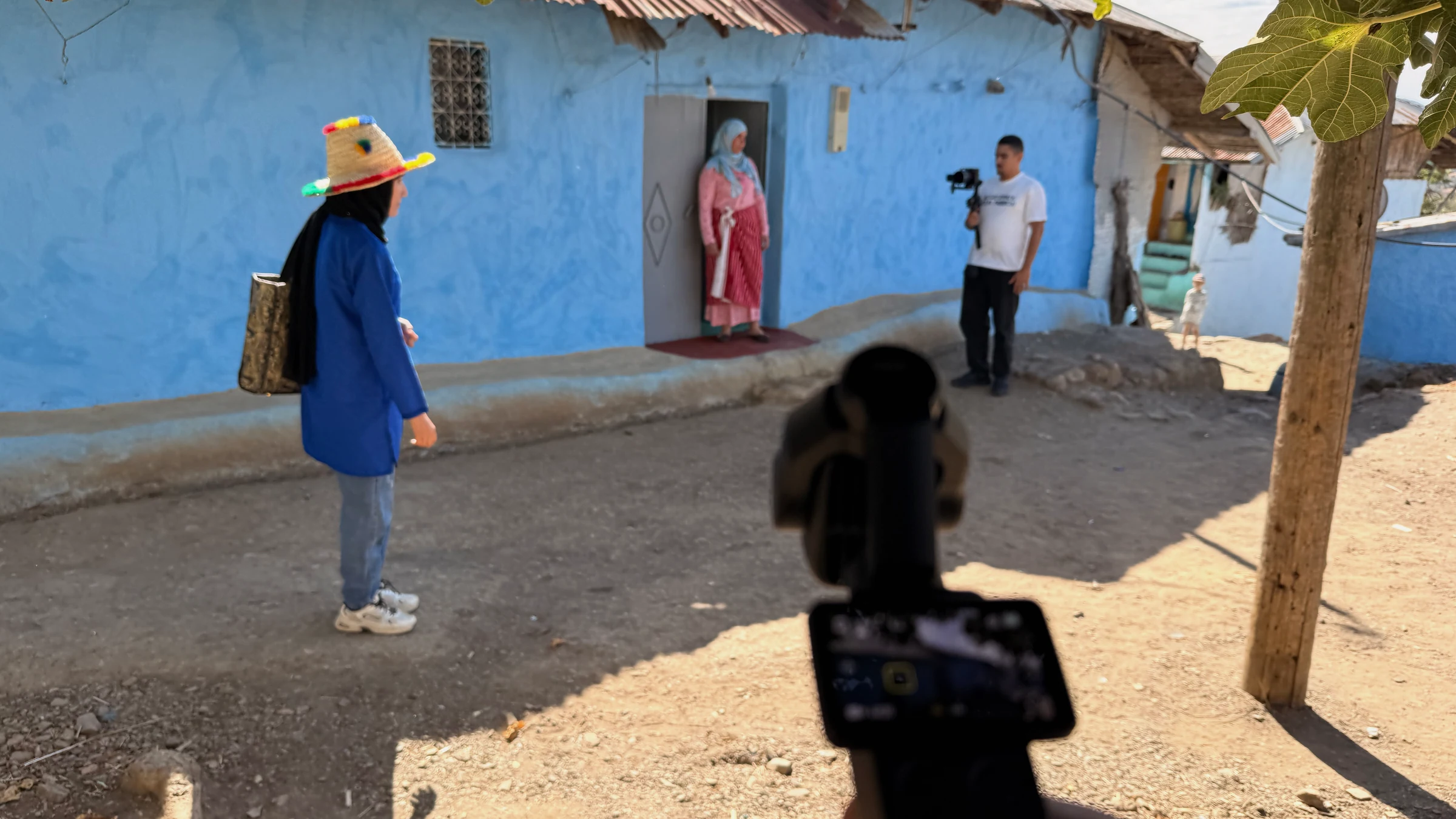 Équipe de tournage en extérieur devant une façade bleue au Maroc.