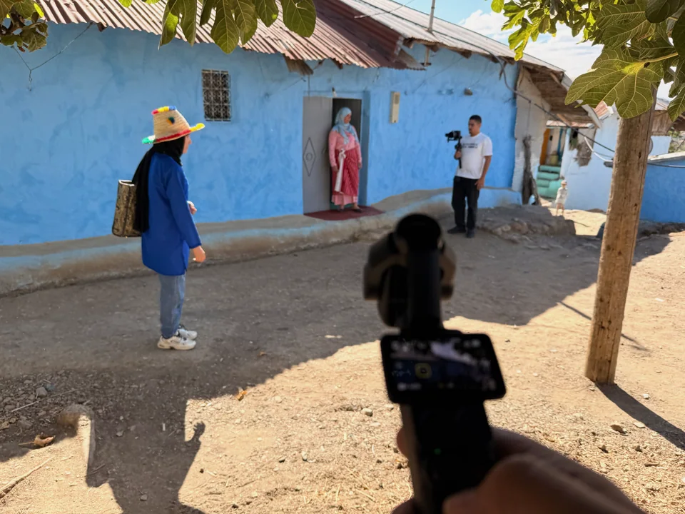 Équipe de tournage devant une façade bleue au Maroc.